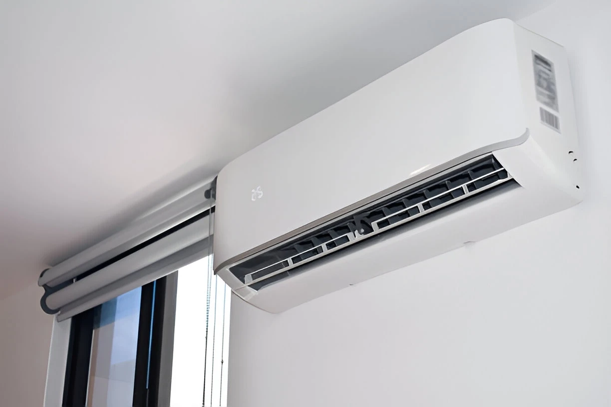 Wall-mounted air conditioner blowing cool air inside a modern room.